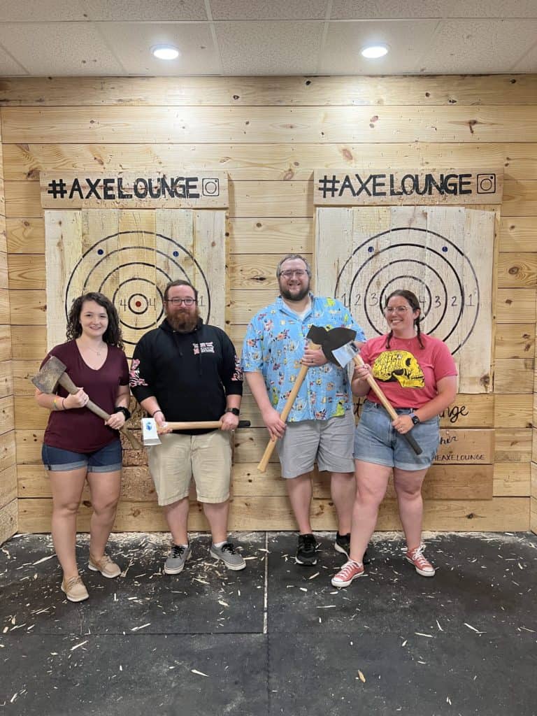 group of friends holding axes at an indoor axe throwing lane