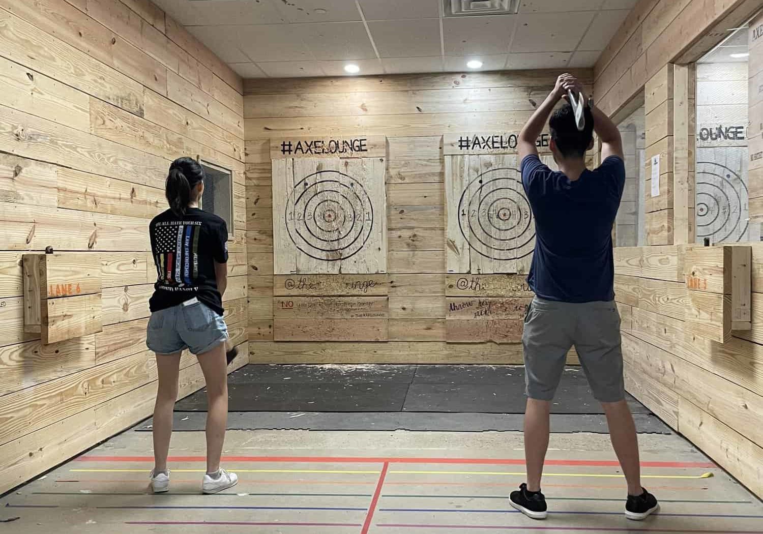 a man and a woman throwing axes at an indoor axe throwing lane