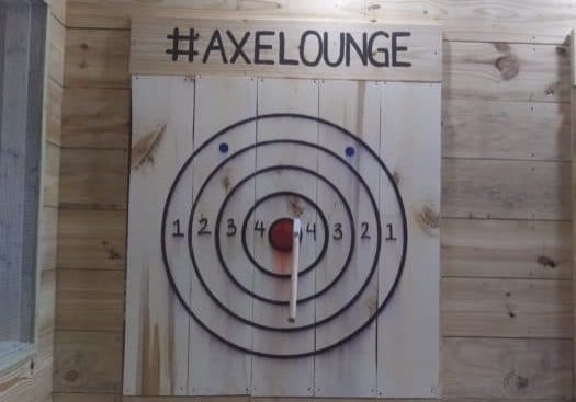 an axe thrown at an indoor target hitting the bullseye